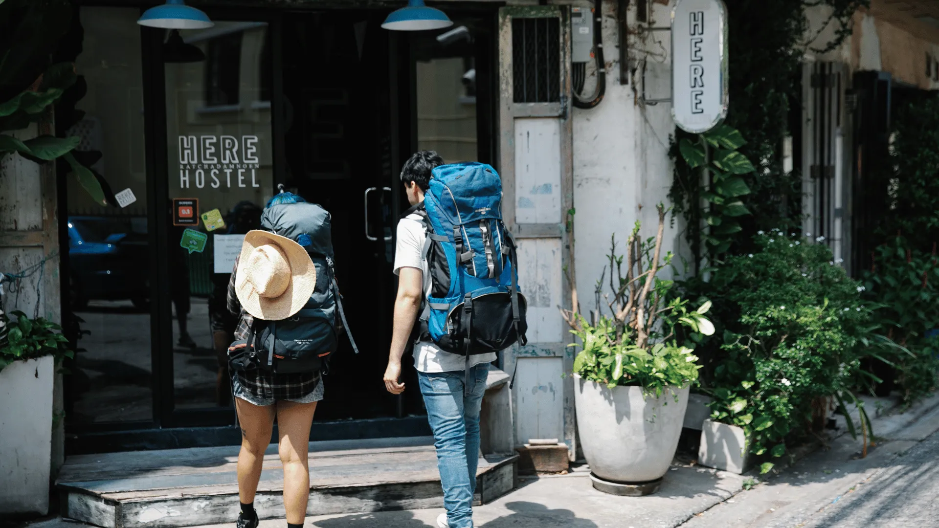 Deux backpackers en Programme Vacances-Travail (PVT) entrant dans leur auberge de jeunesse